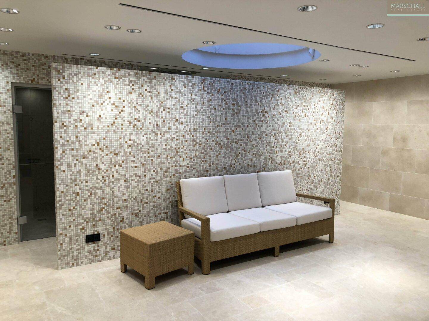 Entspannungsbereich im Wellnessbereich mit bequemer Couch und Mosaikwand.
