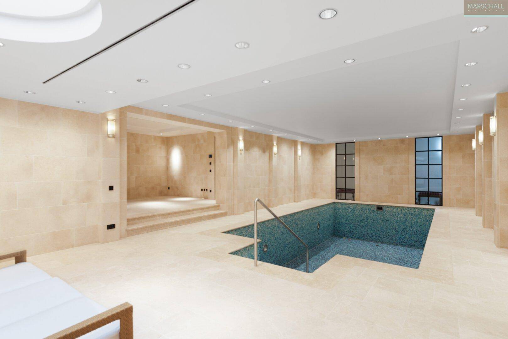 Geräumiger Innenpoolbereich mit hellem Steinboden und Zugang zu weiteren Wellnessbereichen.