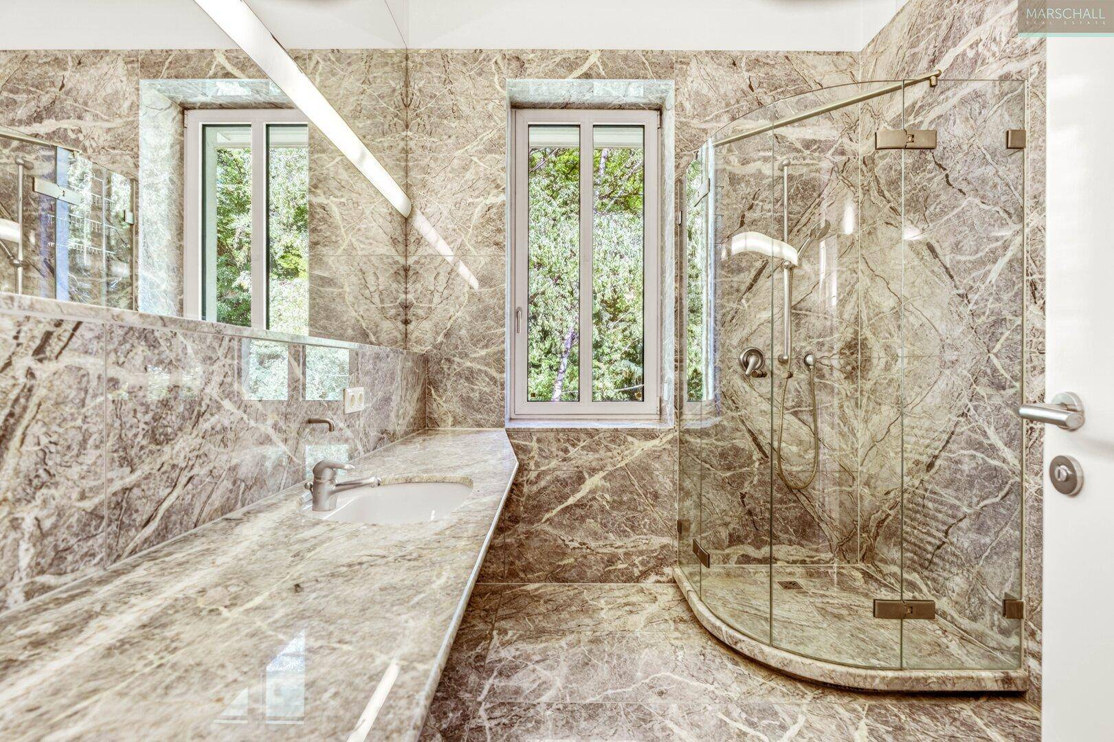 Modernes Badezimmer mit Marmorfliesen, großer Dusche und Fenster.