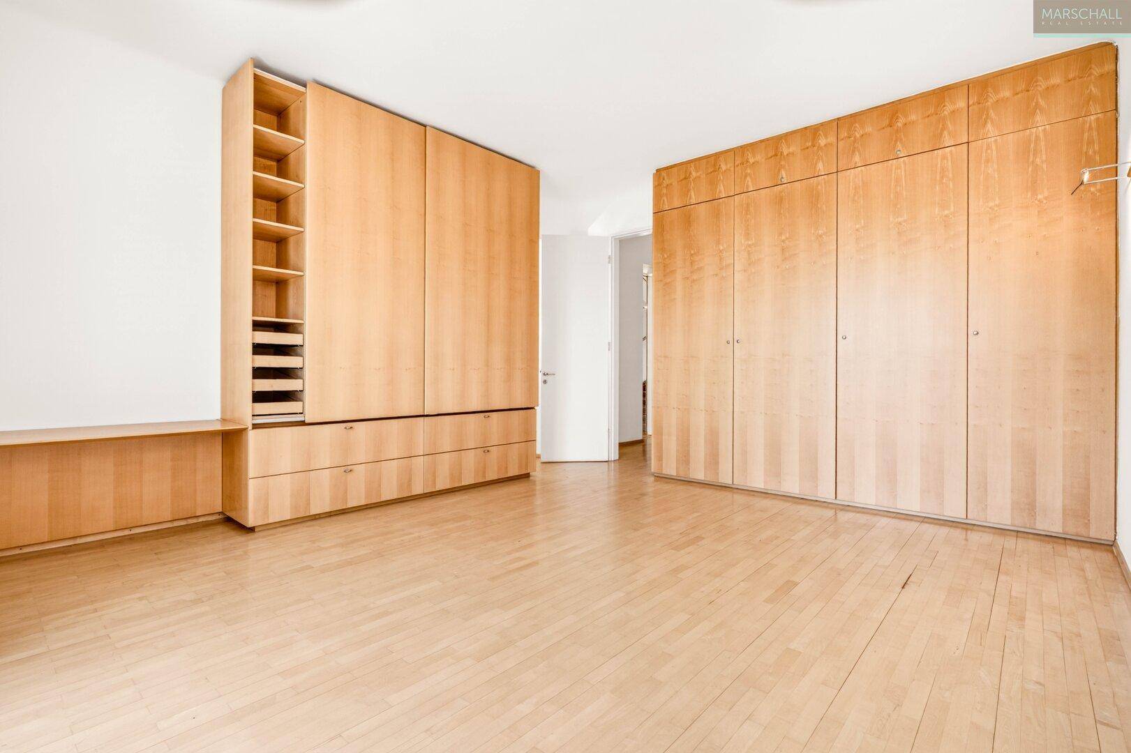 Schlafzimmer mit großen Einbauschränken und hellem Holzboden.