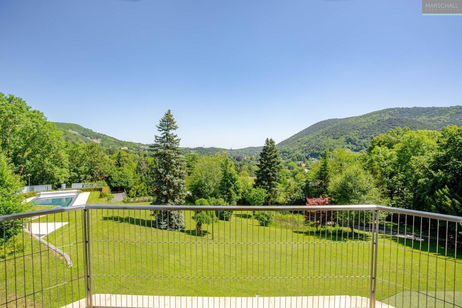 Großer Balkon mit Metallgeländer und weitem Blick auf die grüne Landschaft.