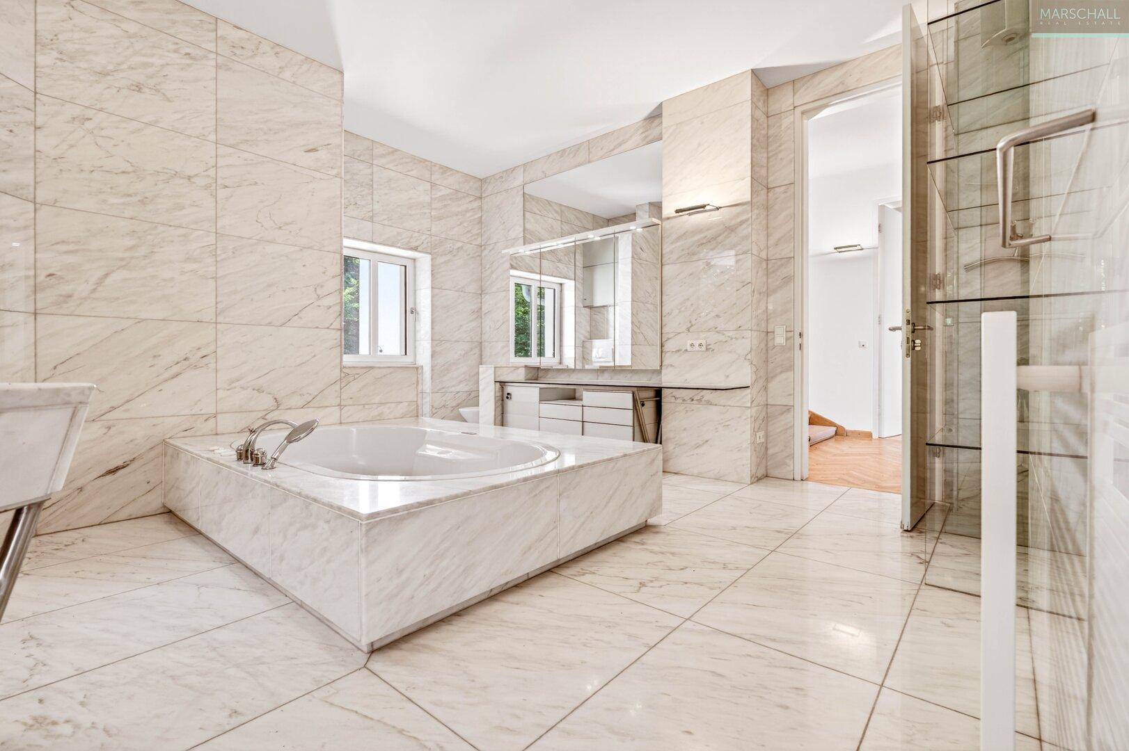 Luxuriöses Badezimmer mit Marmorfliesen, großer Badewanne und Doppelwaschbecken.