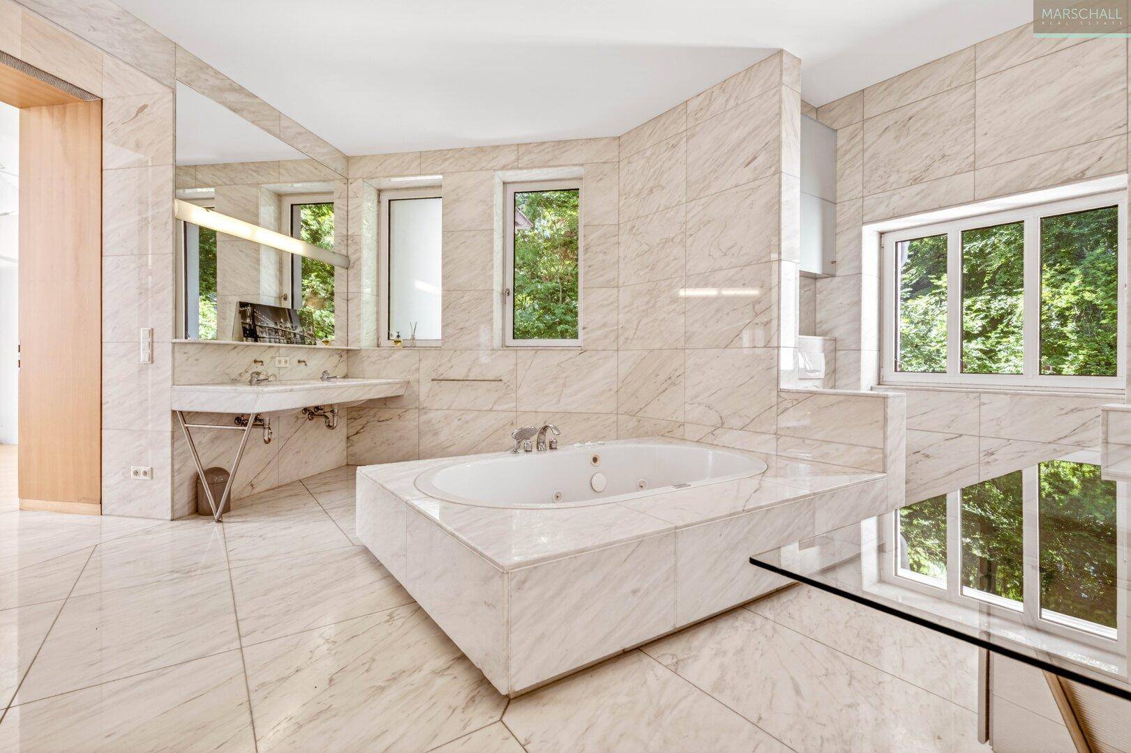 Elegantes Marmorbad mit integrierter Badewanne, zwei Fenstern und viel Tageslicht.
