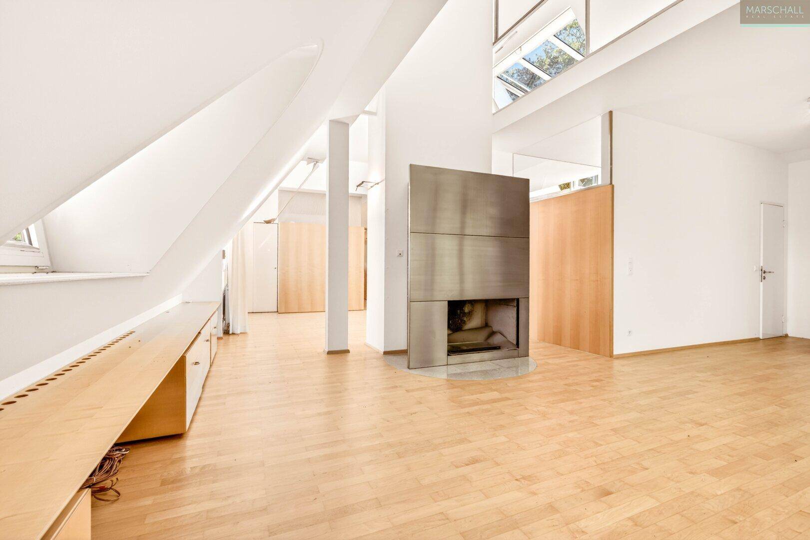 Offener Wohnbereich mit modernem Kamin, Holzboden und hohen, schrägen Decken.