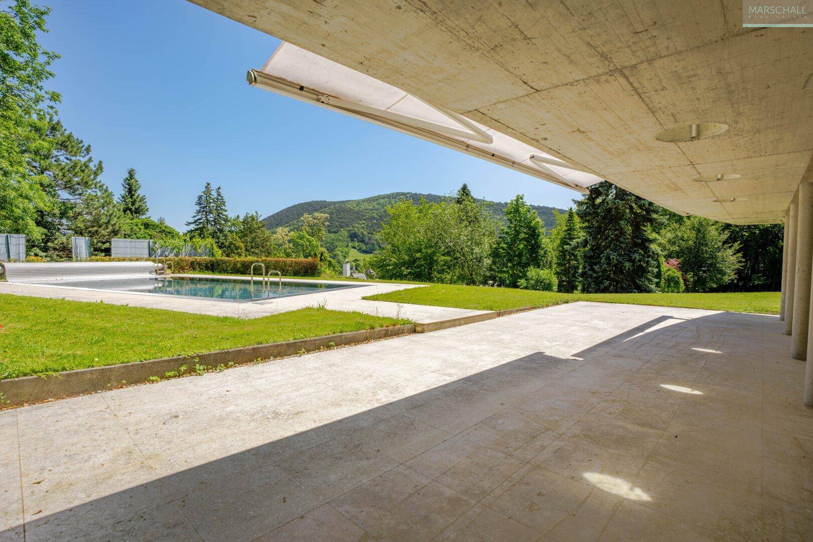 Überdachte Terrasse am Poolbereich mit weitem Blick auf die grüne Hügellandschaft.