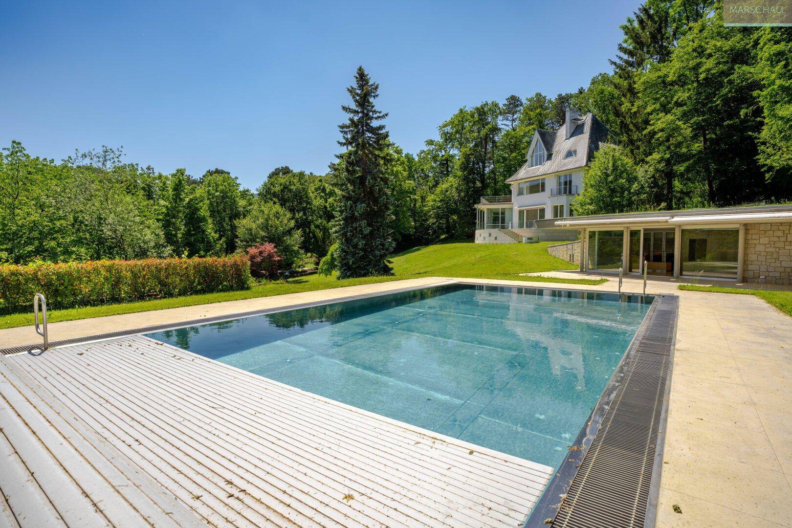 Großer Außenpool in weitläufiger Gartenanlage mit Blick auf das Haupthaus.