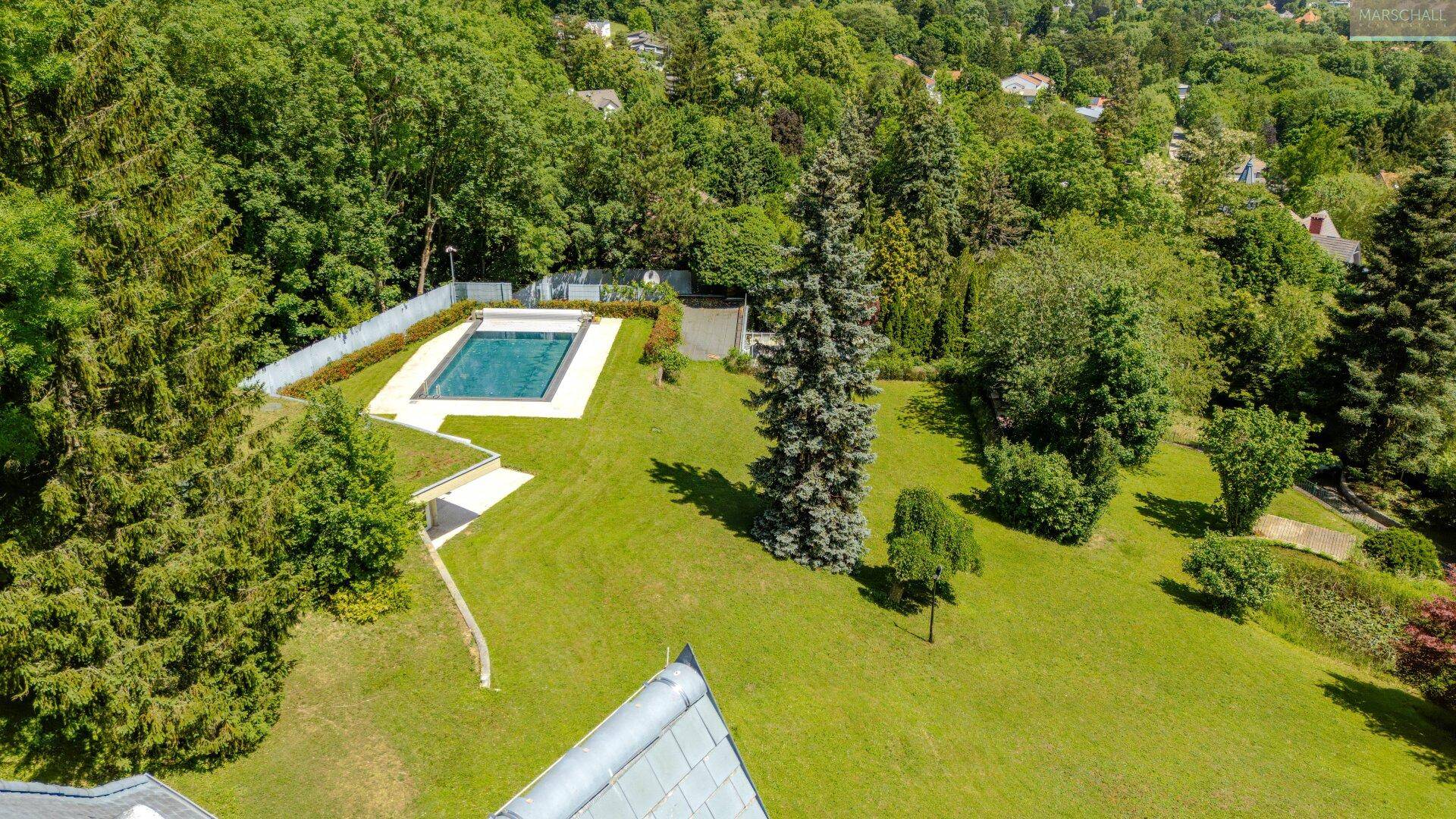 Luftaufnahme des Anwesens mit großem Garten, Pool und Gebäudedach.