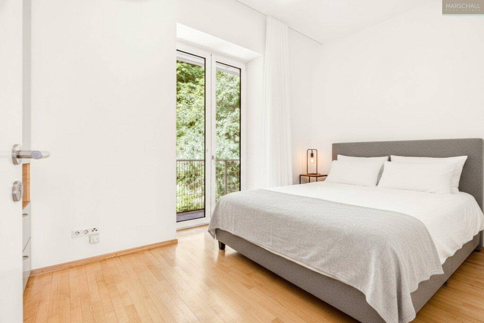 Modernes Schlafzimmer mit Holzboden und Zugang zu einem französischen Balkon.