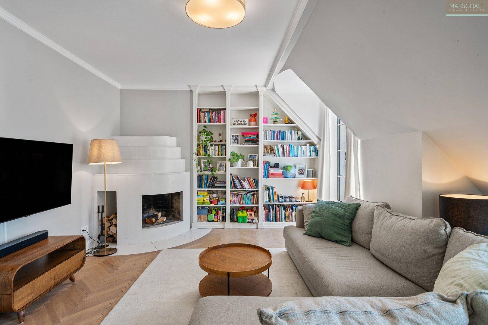 Gemütliches Wohnzimmer mit Kamin, integrierten Bücherregalen und Fischgrätparkett.