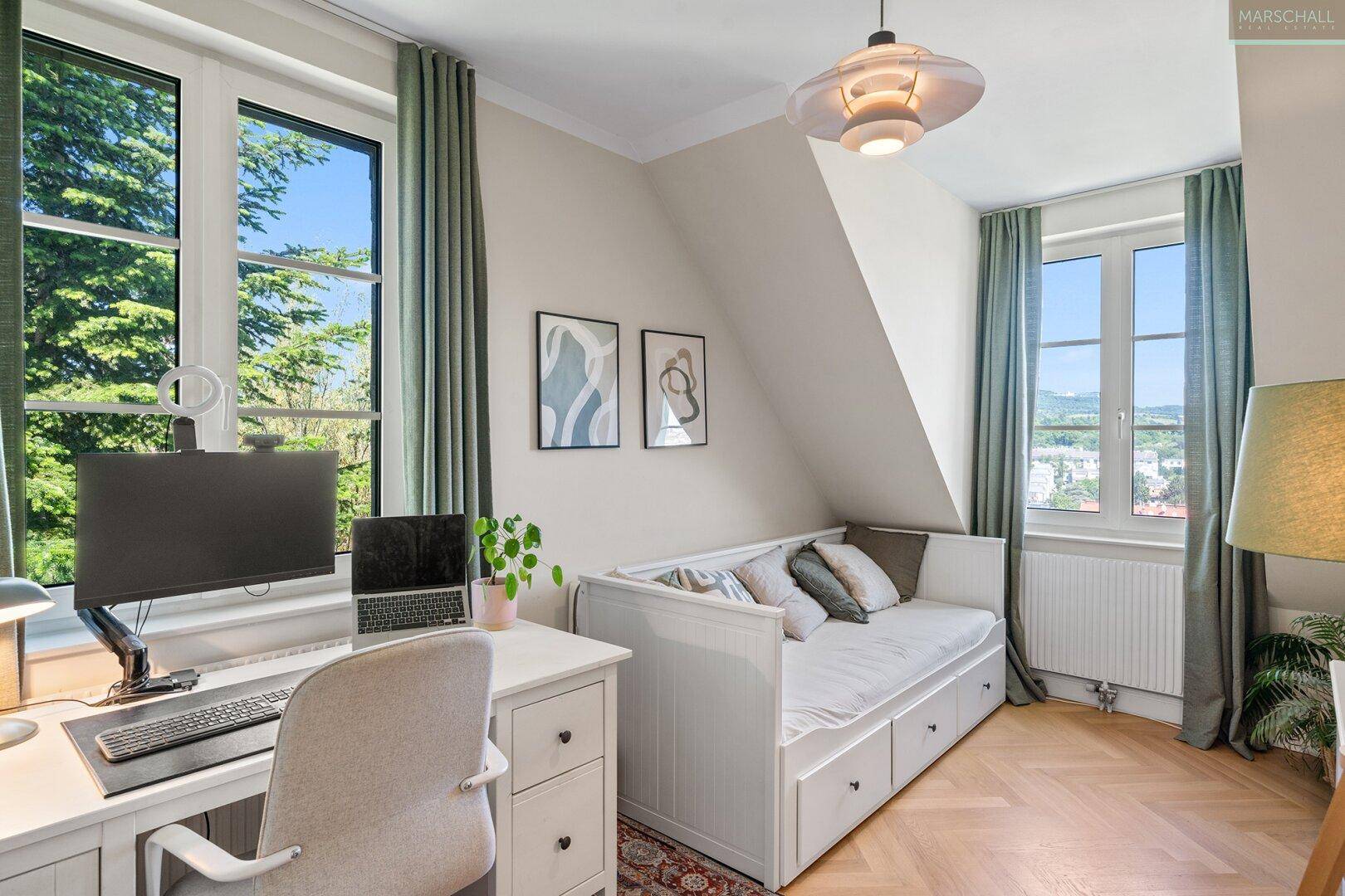 Helles Arbeitszimmer mit Schreibtisch, Tagesbett, Fischgrätparkett und weitem Ausblick.
