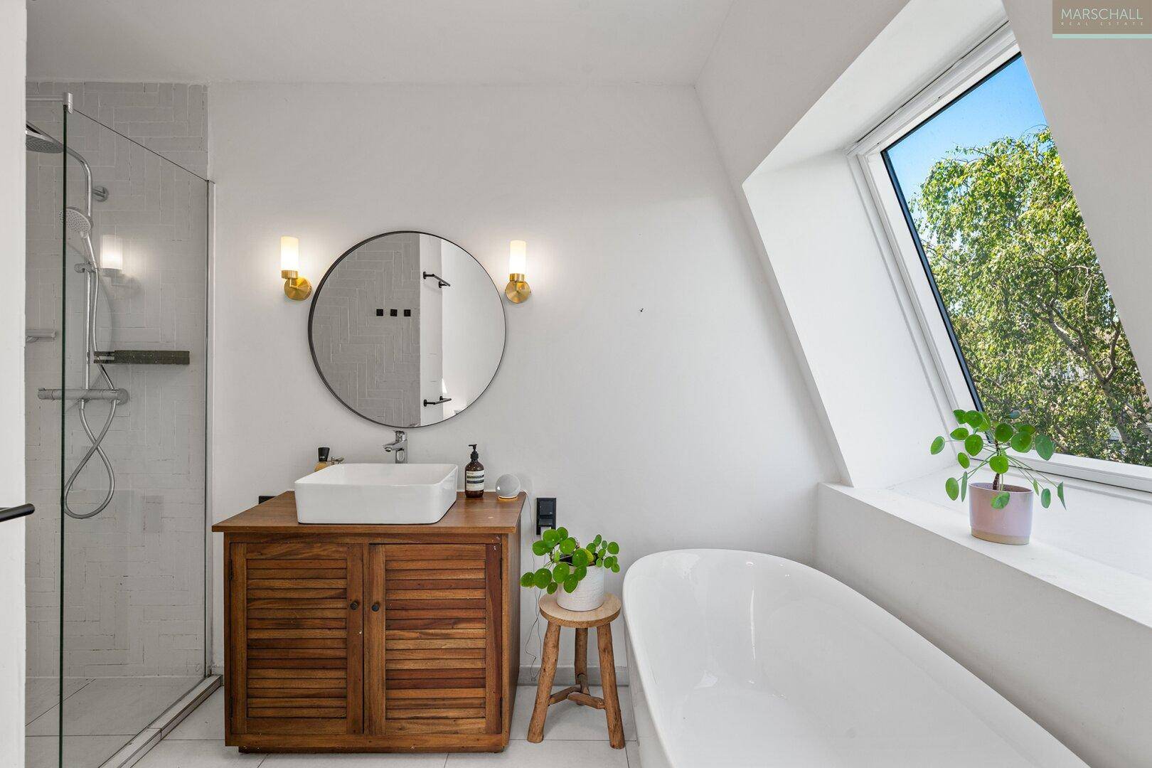 Modernes Badezimmer mit Badewanne, Dusche, Holzwaschtisch und Dachfenster.