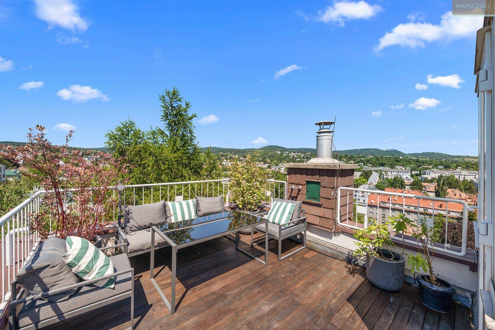 Geräumige Dachterrasse mit Sitzgelegenheiten, Holzboden und weitem Stadtblick.