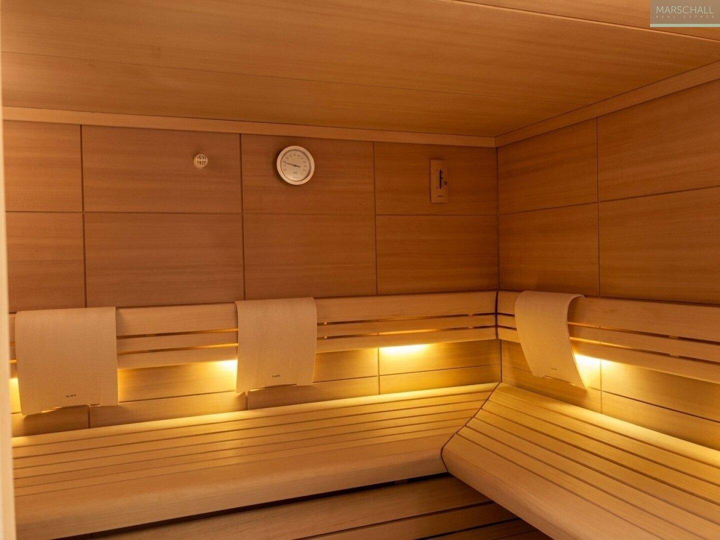 Innenansicht einer modernen Holzsauna mit bequemen Bänken und indirekter Beleuchtung.
