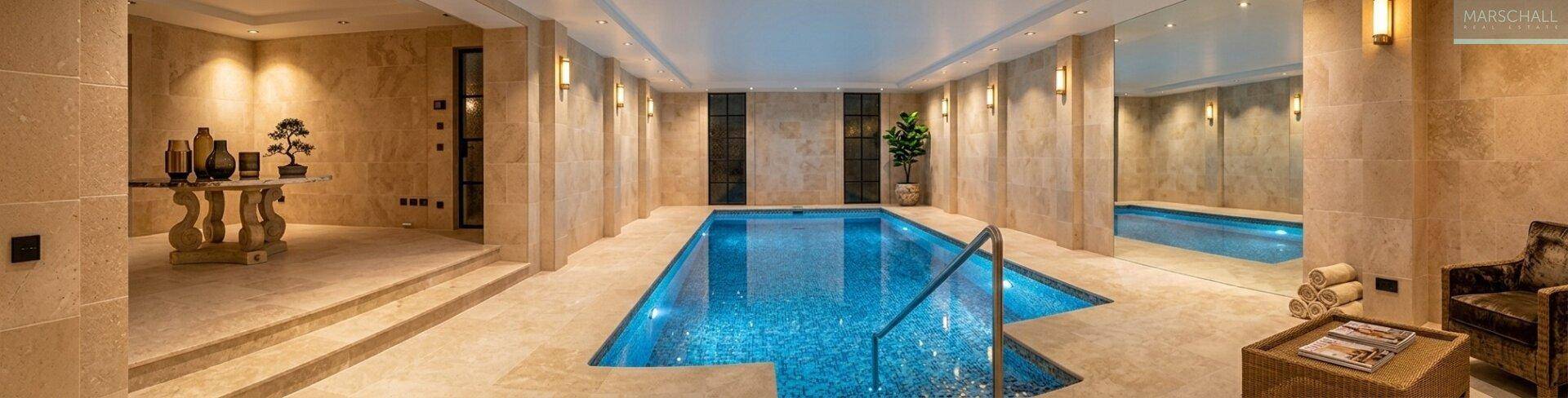 Luxuriöser Innenpool mit blauen Mosaikfliesen und elegantem Steinboden.