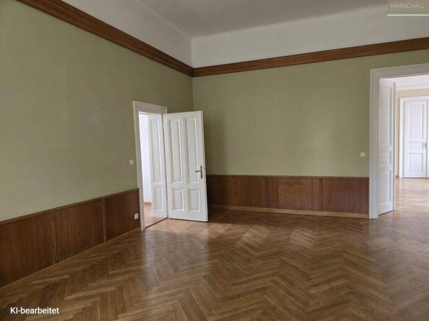 Klassischer Raum mit Fischgrätparkett, Holzvertäfelung und hohen Decken, bereit zur Renovierung.