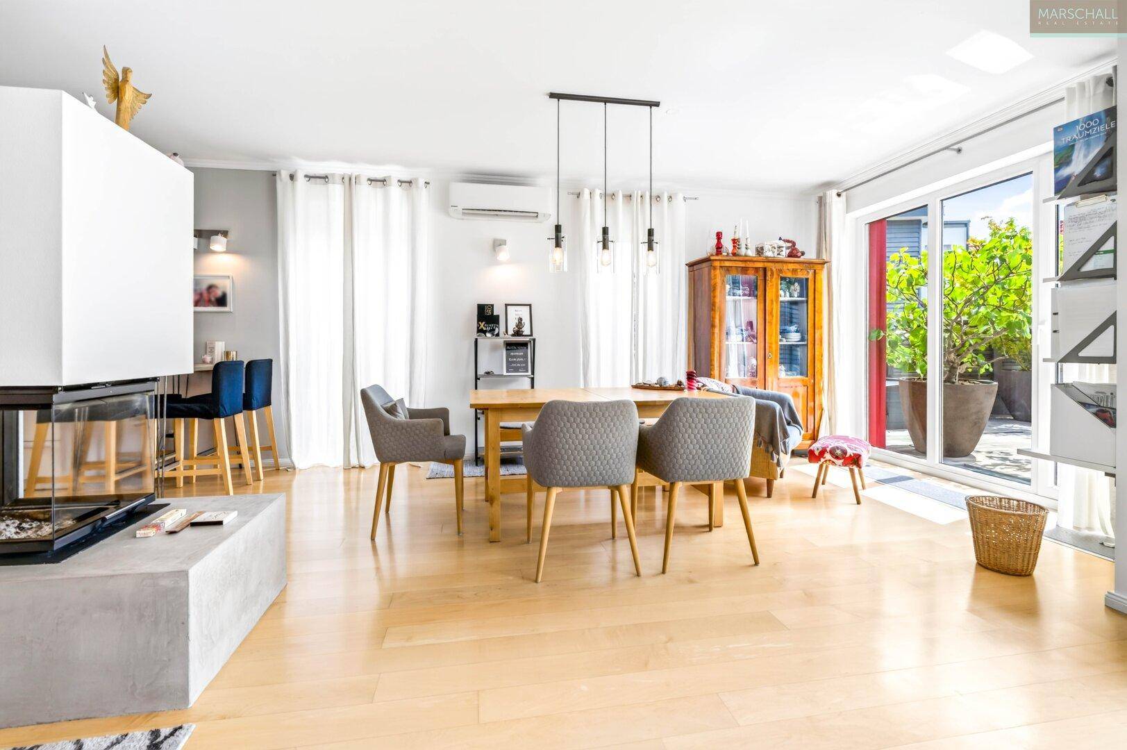 Heller Essbereich mit Holztisch, Stühlen und Zugang zur Terrasse durch große Fenster.