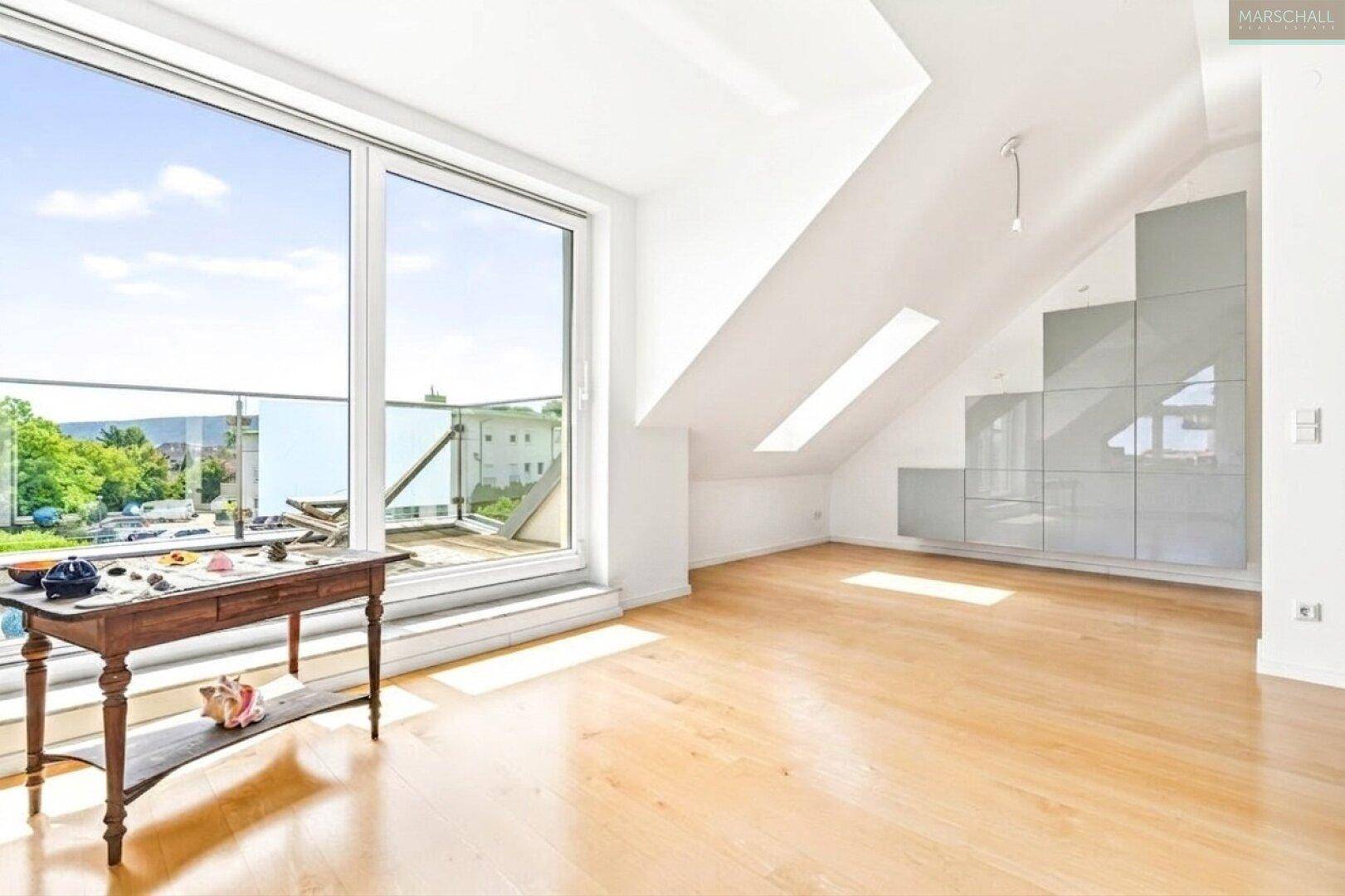 Heller Dachgeschossraum mit Holzboden, Dachfenstern und Zugang zur Dachterrasse.