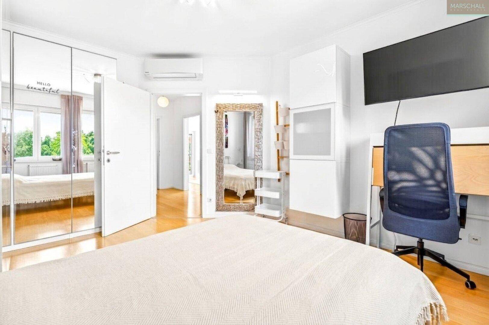 Helles Schlafzimmer mit Doppelbett, Spiegelschränken, Schreibtisch und Klimaanlage.