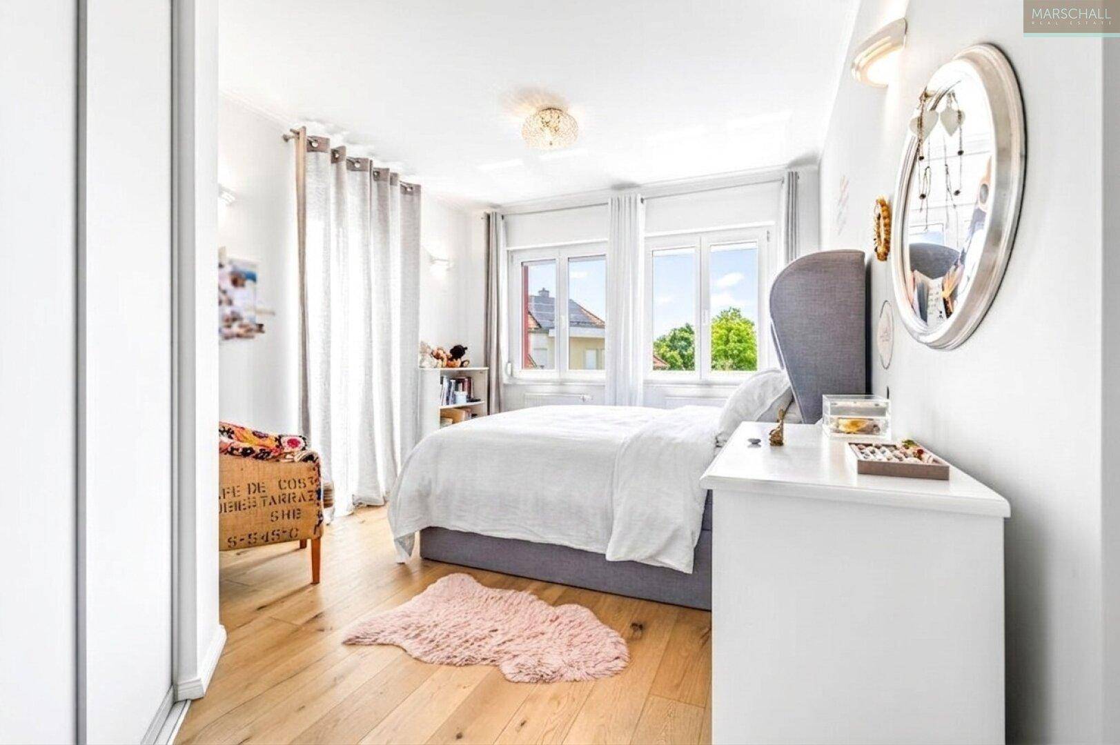 Gemütliches Schlafzimmer mit Holzboden, großem Fenster und modernem Bett.