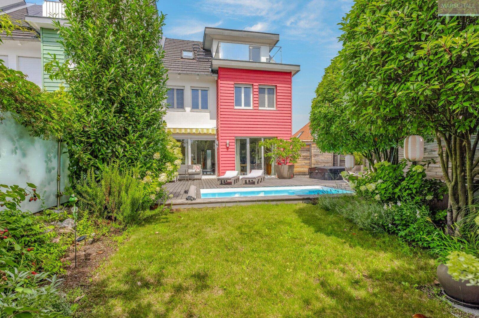 Großer Garten mit Rasenfläche, Bäumen und Blick auf das moderne Reihenhaus mit Pool.