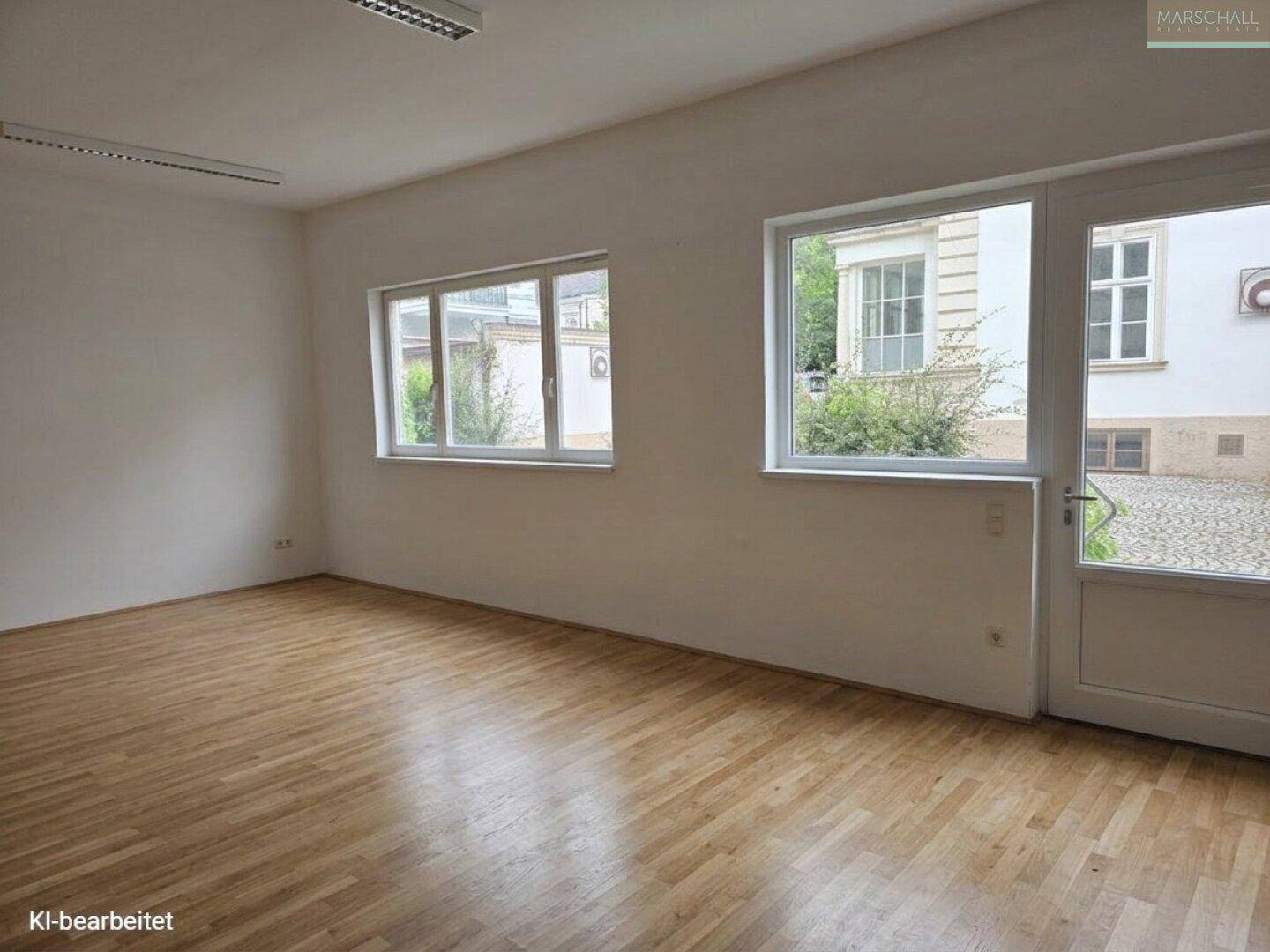 Heller Raum mit Laminatboden und Fenstern zum Innenhof, ideal für Büro oder Hobby.