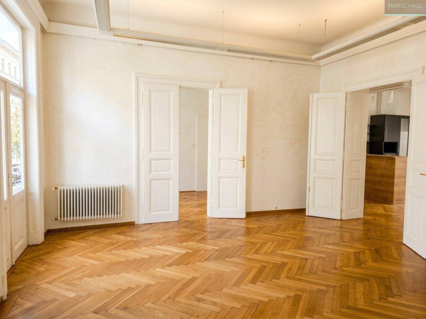 Heller Raum mit Fischgrätparkett, hohen Decken und Flügeltüren, bereit zur individuellen Gestaltung.