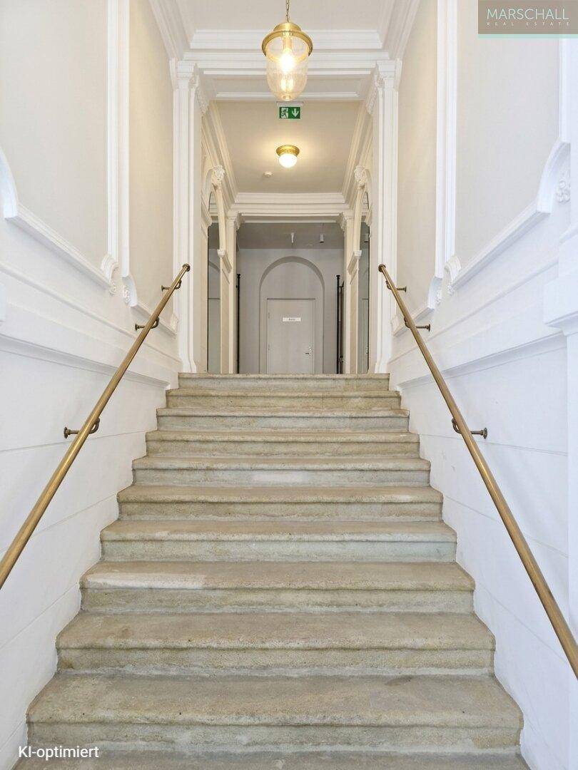 Repräsentatives Treppenhaus mit Steinstufen und eleganten Handläufen in einem historischen Gebäude.