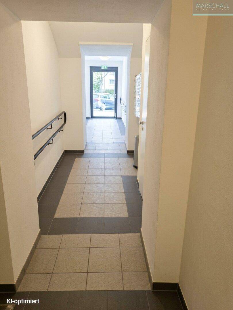 Moderner Flur mit Fliesenboden und Zugang zum Außenbereich durch eine Glastür.