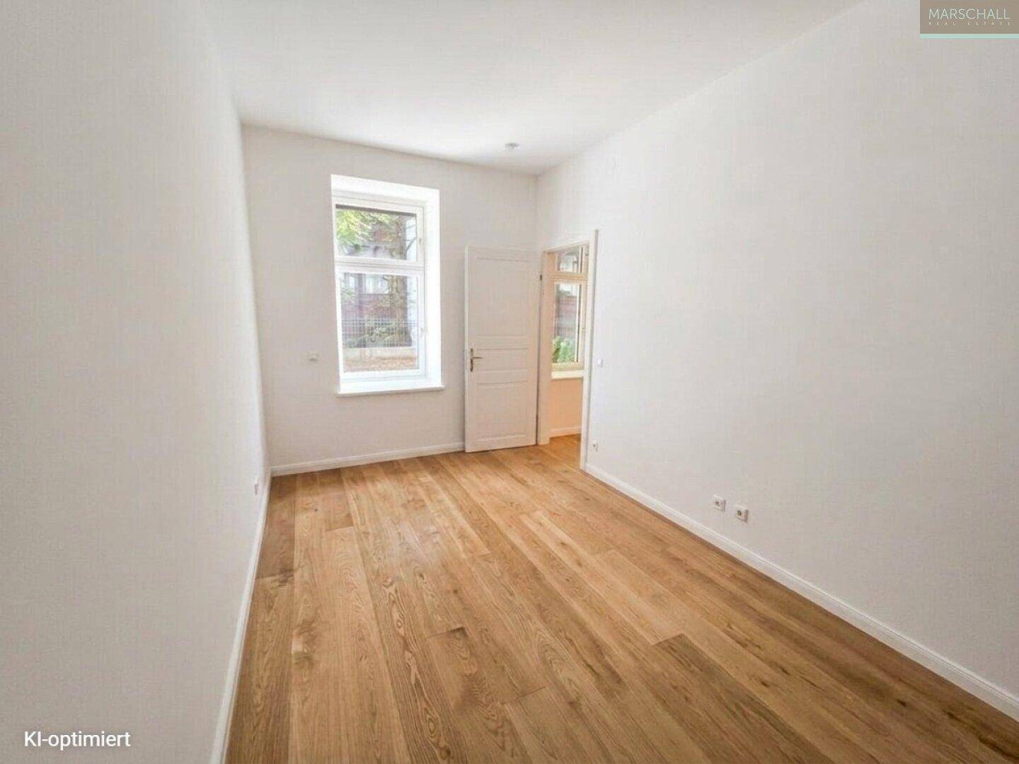 Helles Schlafzimmer mit Eichenparkettboden und einem Fenster mit Blick nach draußen.