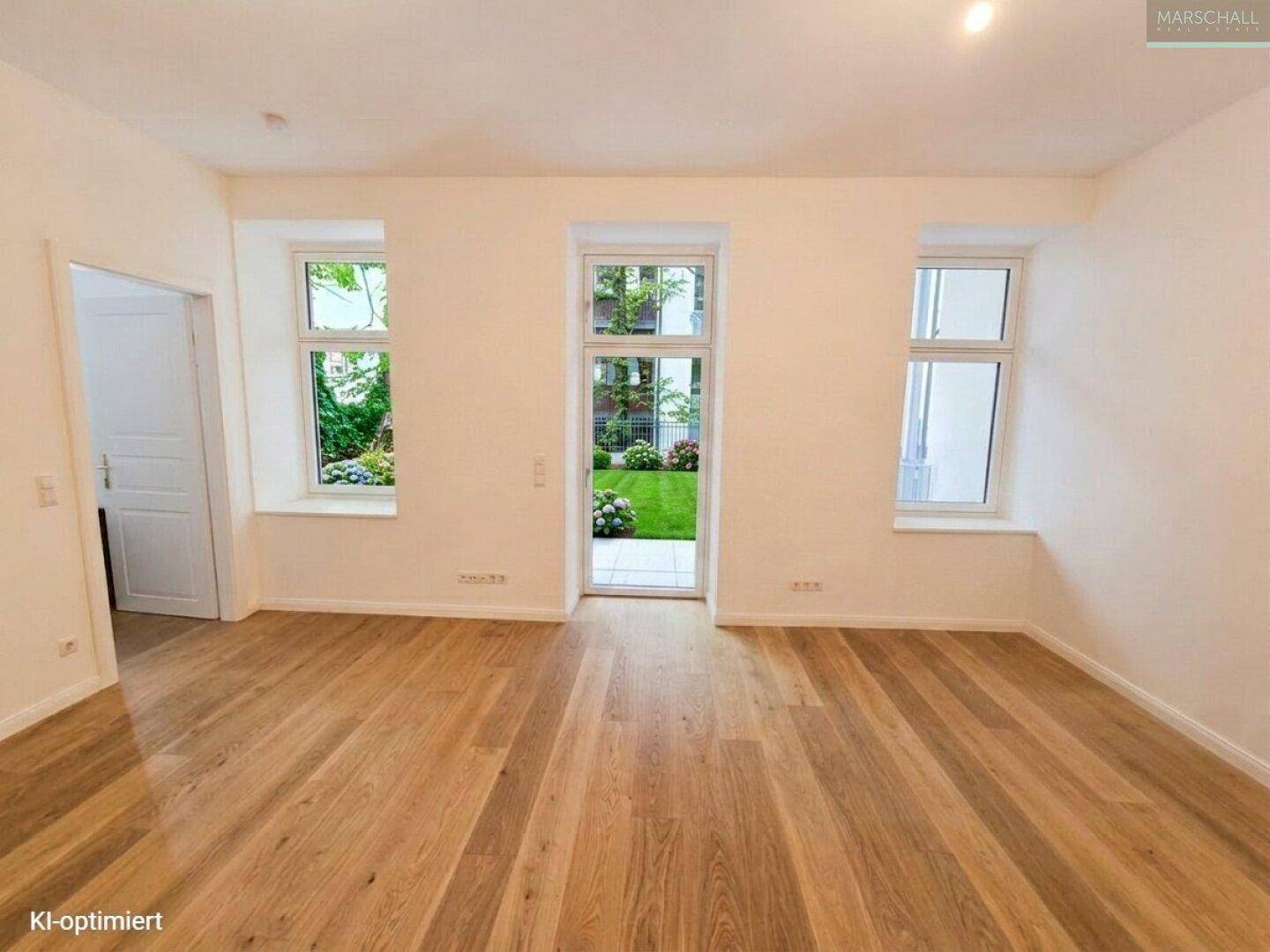 Heller Wohnraum mit Eichenparkett und großen Fenstern, die den Blick in den Garten freigeben.