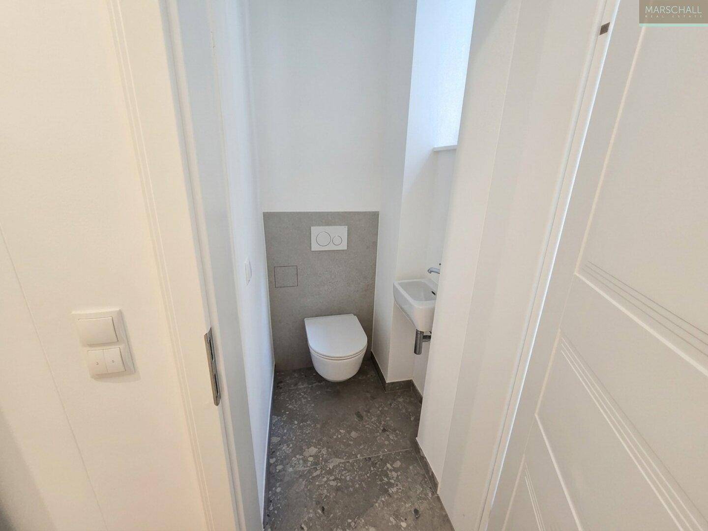 Kleines Gäste-WC mit wandhängender Toilette und Handwaschbecken, in modernem Design.