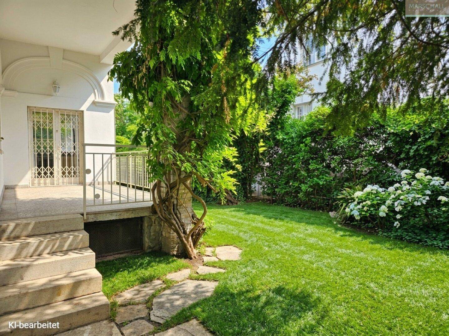 Kleiner Terrassenbereich mit Treppe, die zu einem gepflegten Rasen und Garten führt.