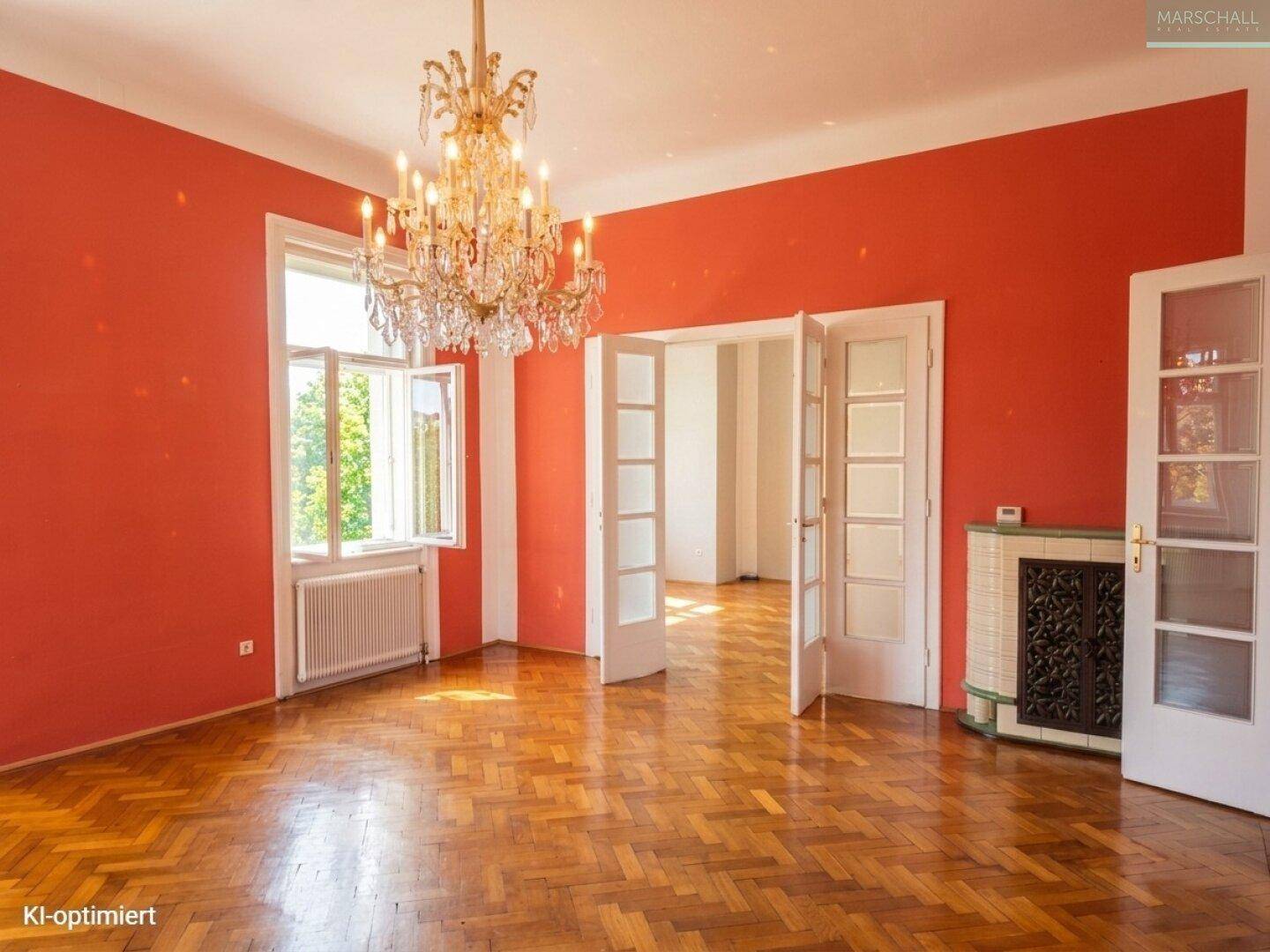 Helles Wohnzimmer mit Fischgrätparkett, roter Wandfarbe und großem Fenster.