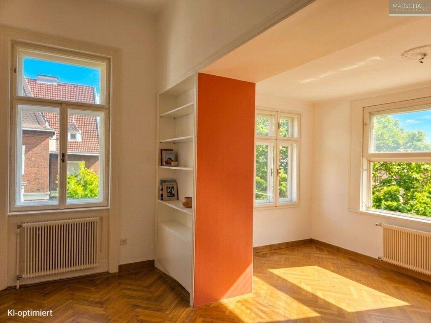 Lichtdurchflutetes Wohnzimmer mit Parkettboden, eingebautem Regal und Blick ins Grüne.