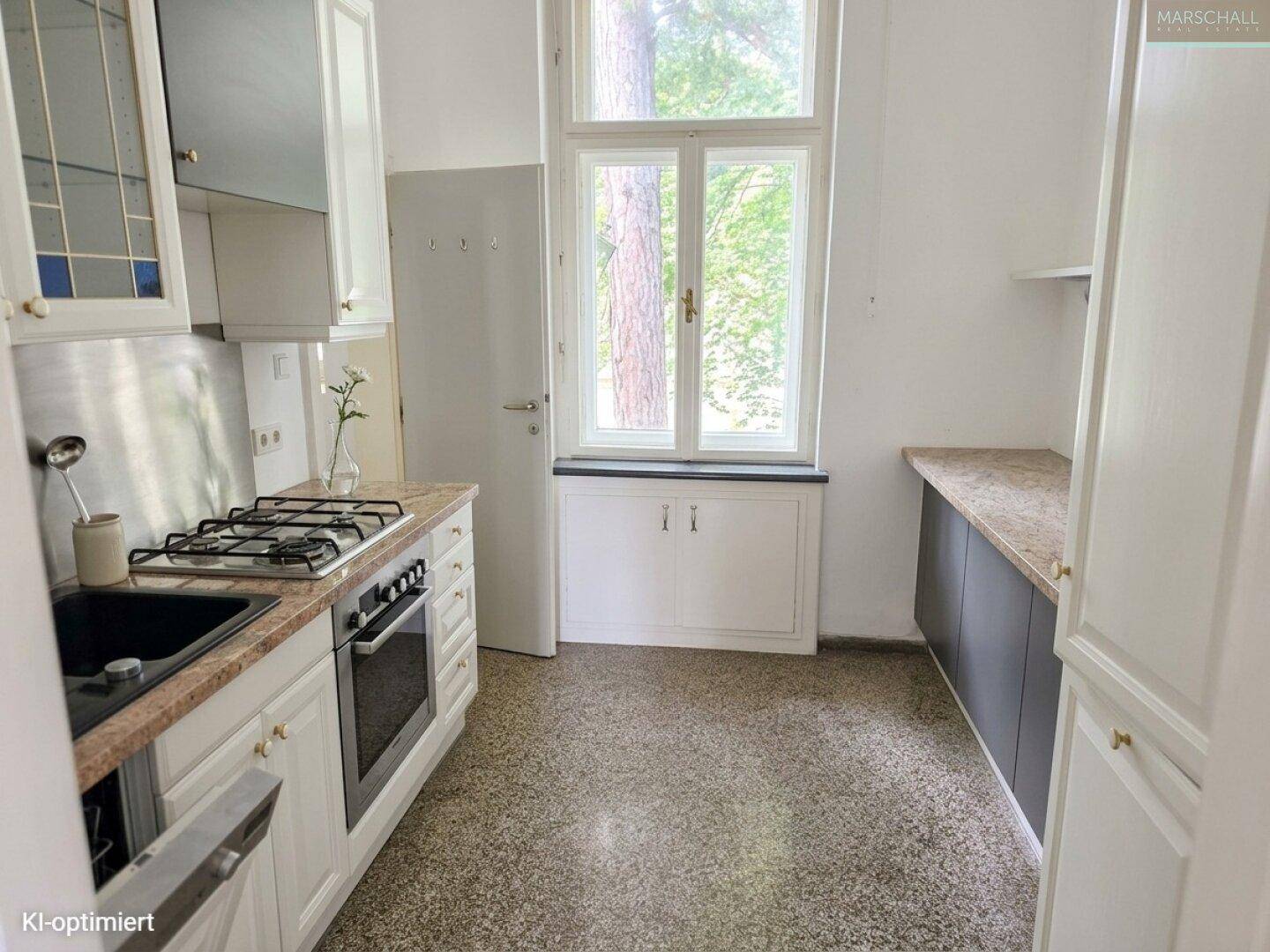 Funktionale Küche mit Gasherd, Granitarbeitsplatte und Fenster mit Blick ins Grüne.