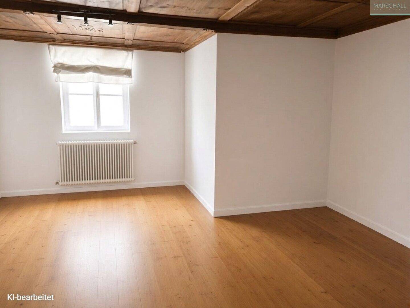 Geräumiges Zimmer mit Holzbalkendecke, Parkettboden und großem Fenster.