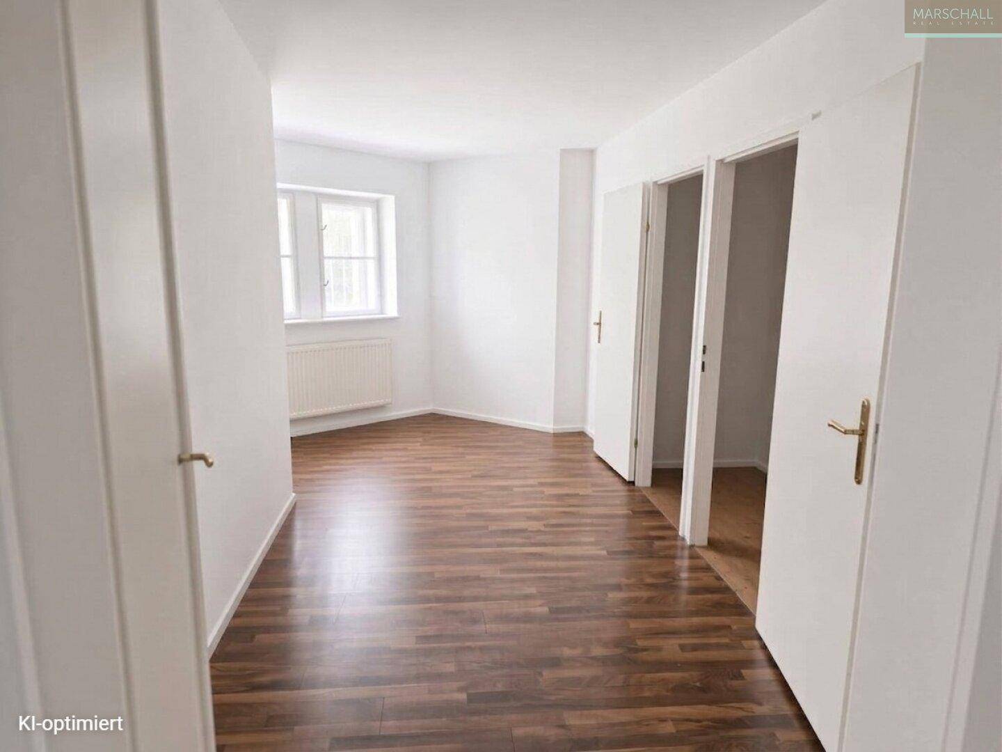 Helles Schlafzimmer mit Laminatboden, weißen Wänden und großem Fenster.