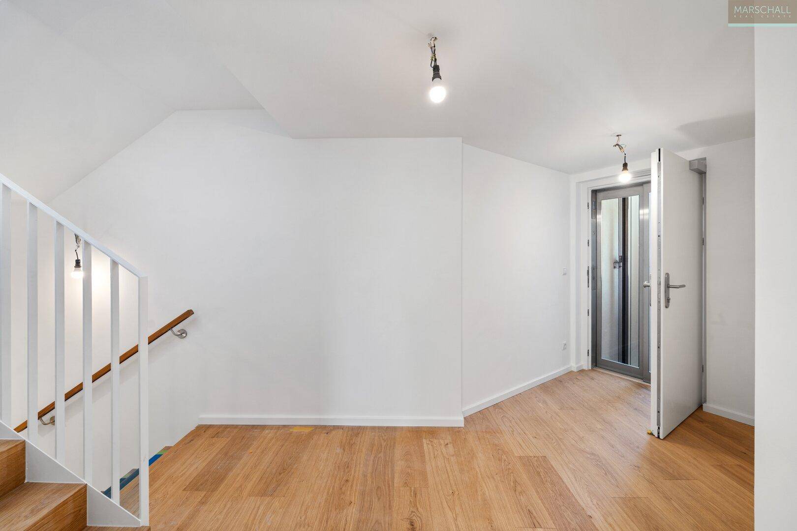 Heller Flur mit Holztreppe und Eichenparkettboden, der zu weiteren Räumen führt.
