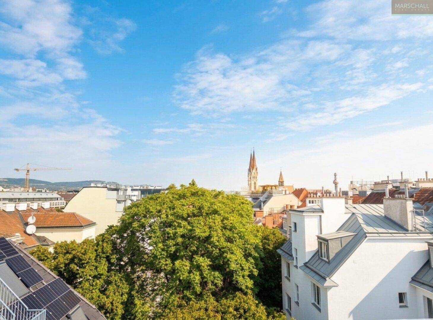 Weitblick über die Stadt mit grünen Bäumen, historischen Gebäuden und einer Kirche im Hintergrund.