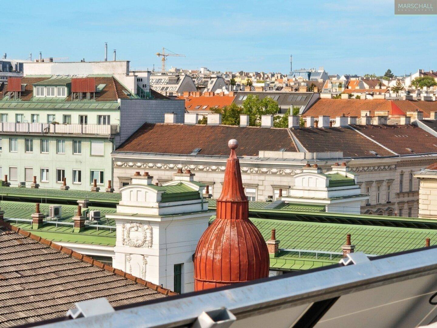 Stadtansicht von oben mit markanten Dächern, einem roten Kuppeldach und Solaranlagen im Bild.