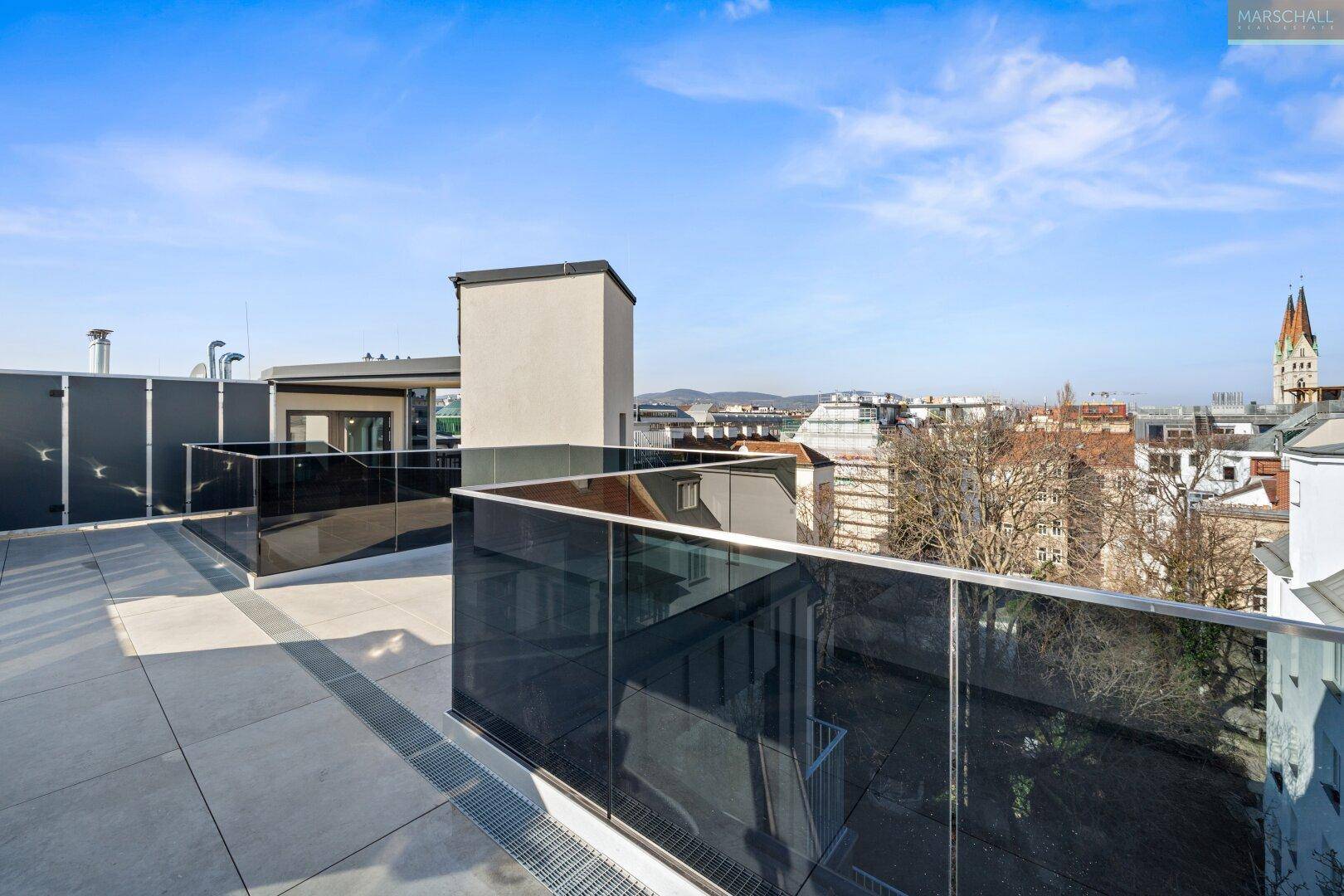 Helle Dachterrasse mit eleganten Glasgeländern und weitem Blick über die städtische Skyline.