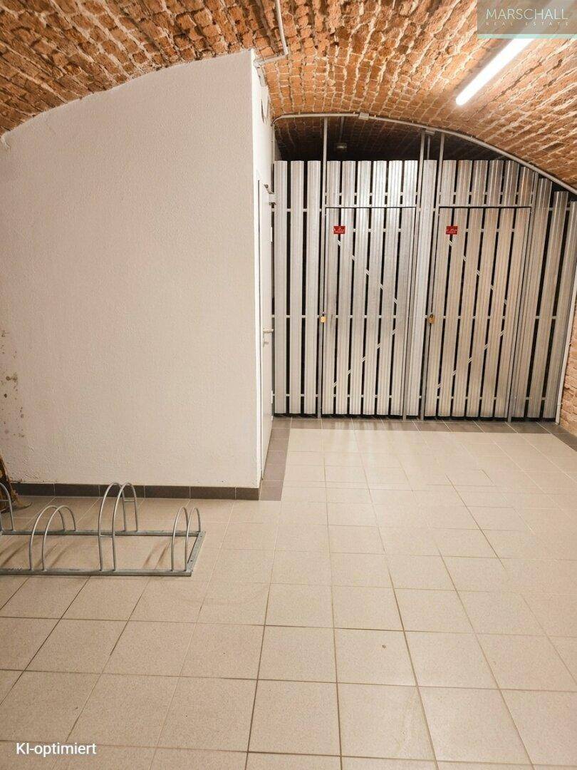 Kellerlagerbereich mit Fliesenboden, Gewölbedecke und Abstellkäfigen sowie Fahrradständern.
