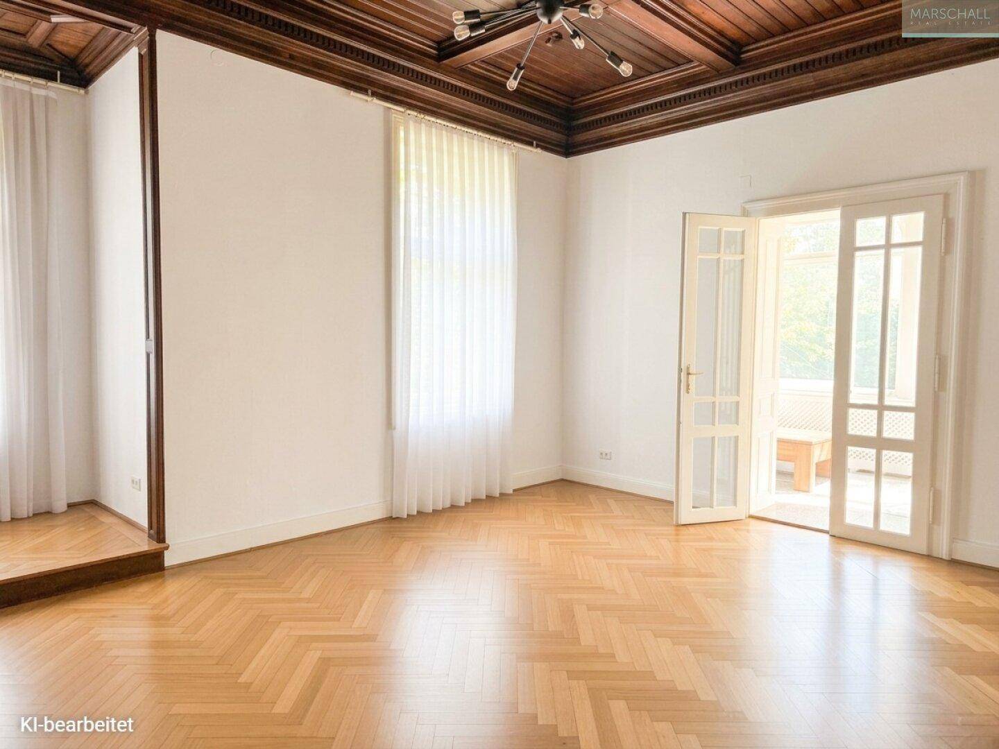 Heller Wohnraum mit Fischgrätparkett und Zugang zu einem weiteren Bereich durch elegante Flügeltüren.
