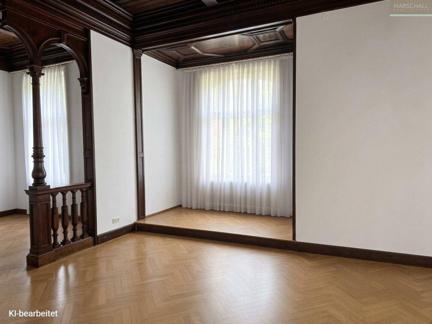 Wohnraum mit Fischgrätparkett, Holzkassettendecke und einem erhöhten Bereich mit Fenster, der viel Licht bietet.