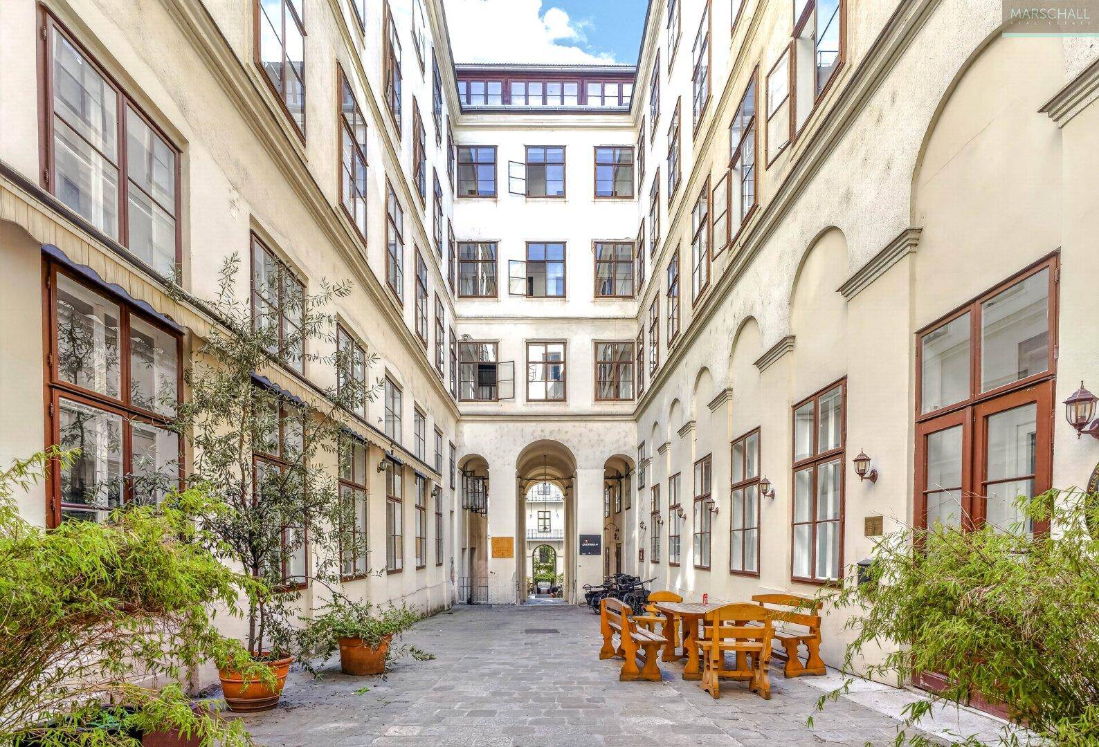 Ruhiger Innenhof mit Sitzgelegenheiten und Pflanzen, umgeben von historischen Gebäuden.