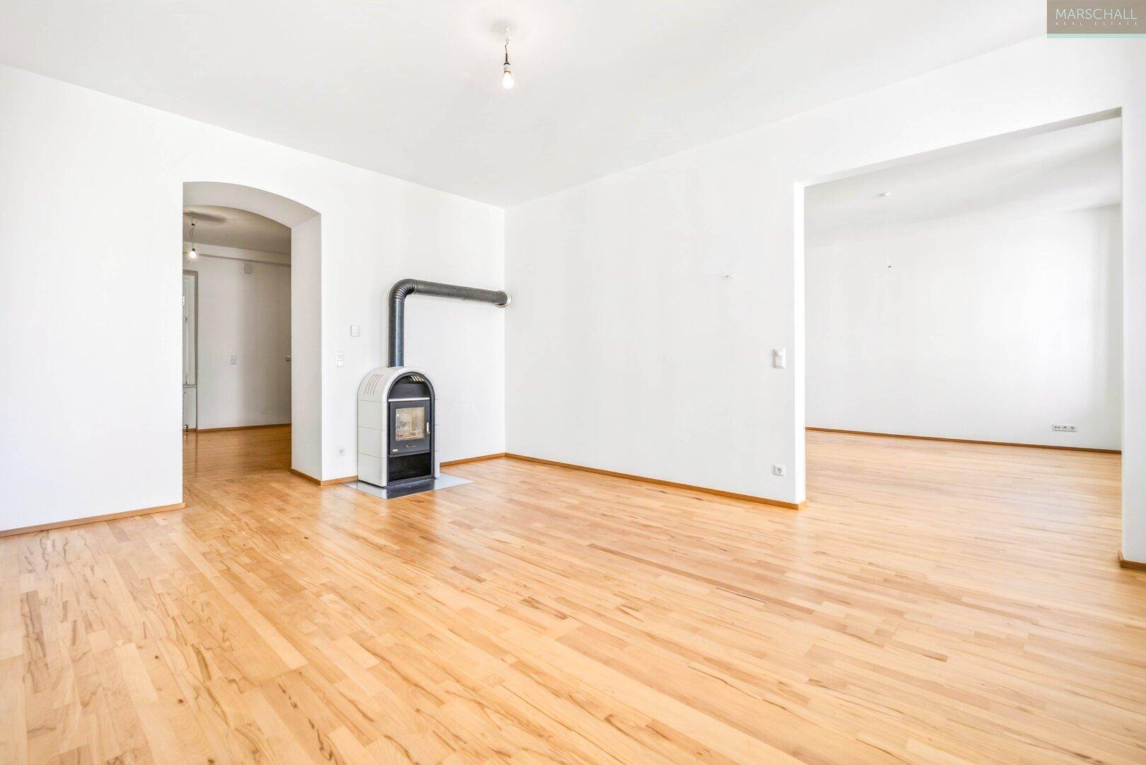 Geräumiger Raum mit Holzboden und einem modernen Holzofen als Heizquelle.
