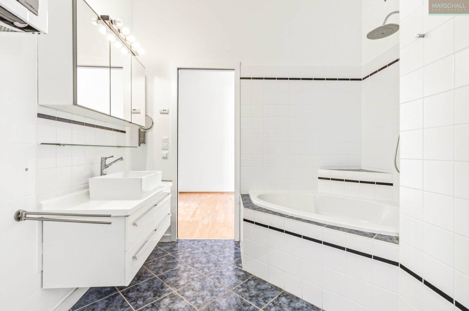 Modernes Badezimmer mit Badewanne, Doppelwaschbecken und dunklen Bodenfliesen.
