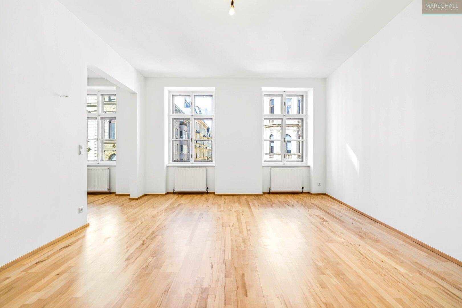 Lichtdurchfluteter Raum mit Holzboden und mehreren Fenstern, bereit zur individuellen Gestaltung.