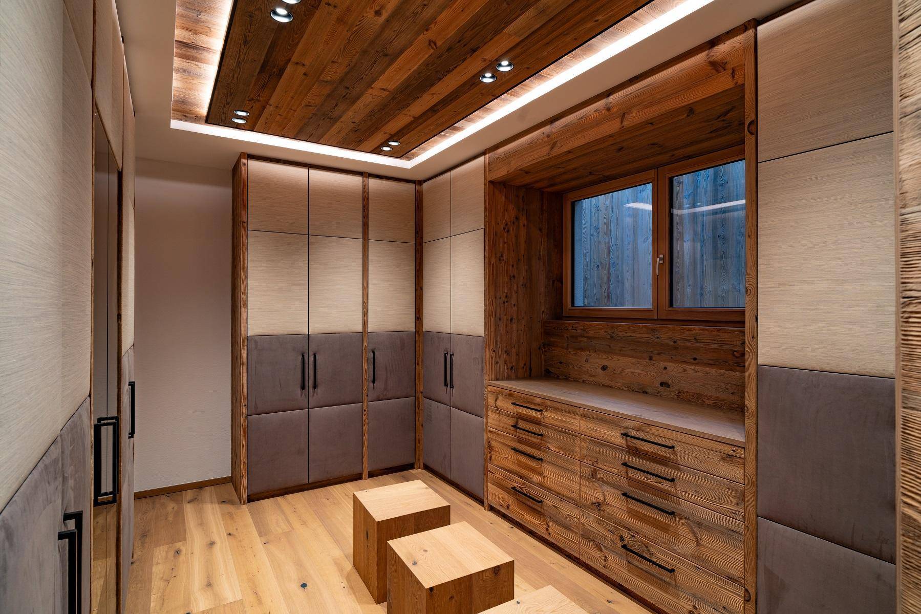 Geräumiger begehbarer Kleiderschrank mit Holzelementen und integrierten Schubladen.