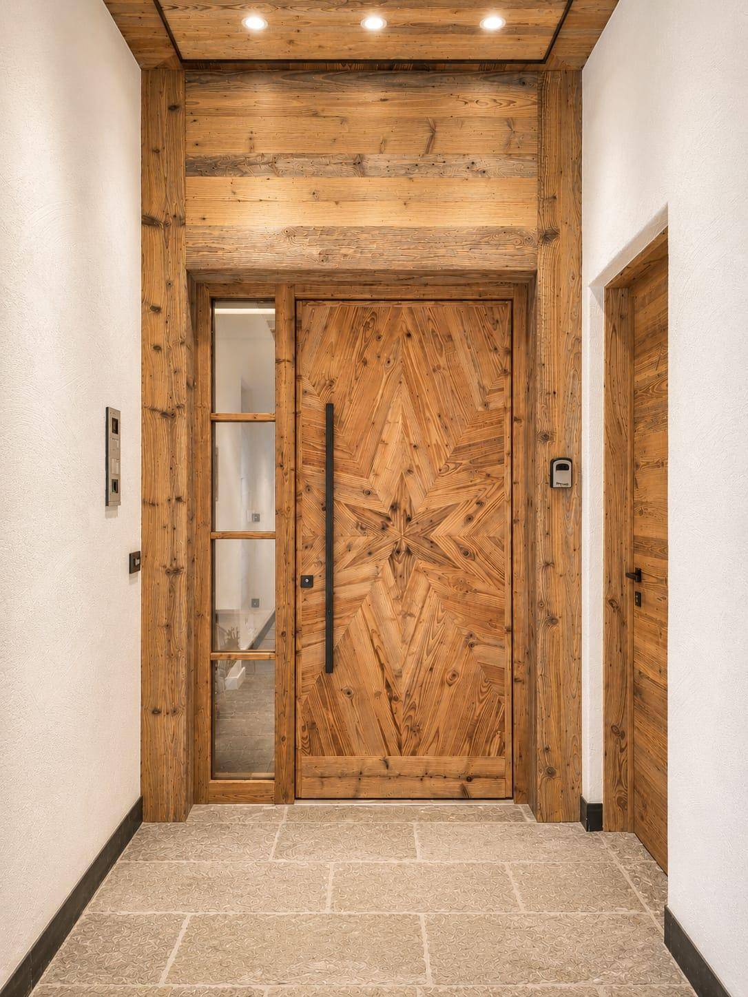 Eingangsbereich mit einer einzigartigen Holztür, Holzvertäfelung und elegantem Steinboden.